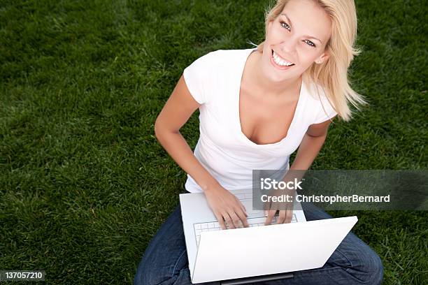 Uśmiechnięta Kobieta Za Pomocą Laptopa Siedząc Na Trawie - zdjęcia stockowe i więcej obrazów 20-24 lata
