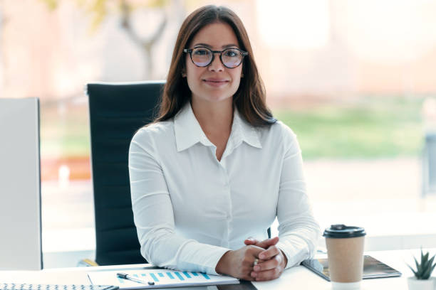 istock Beautiful business woman working with computer while looking at camera in modern startup office. 1370573303