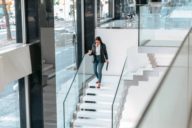 istock Businesswoman working with a digital tablet while drinking coffee going down the office stairs. 1370573500
