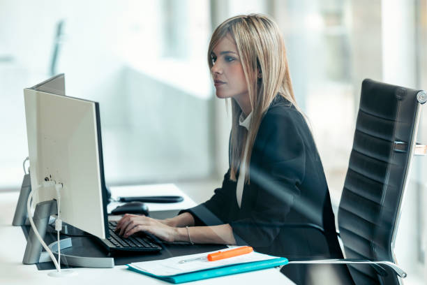 istock Beautiful young business woman working with computer while sitting in desk in modern startup office. 1370573529