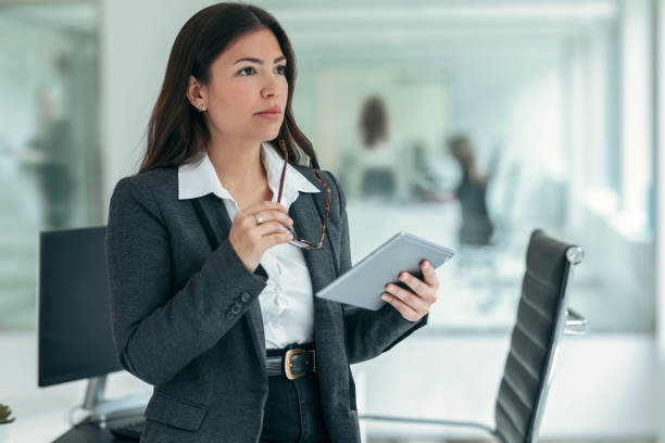 istock Beauty business woman using her digital tablet while working in a modern startup office. 1370573762