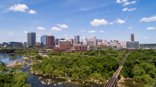 horizonte aéreo de downtown richmond, virgínia. a vista distante sobre o rio james e parques circundantes e áreas naturais de madeira. a ferrovia na ponte. - richmond virginia virginia skyline urban scene - fotografias e filmes do acervo