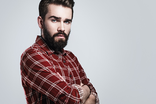 Portrait of handsome bearded man wearing checkered shirt on gray background
