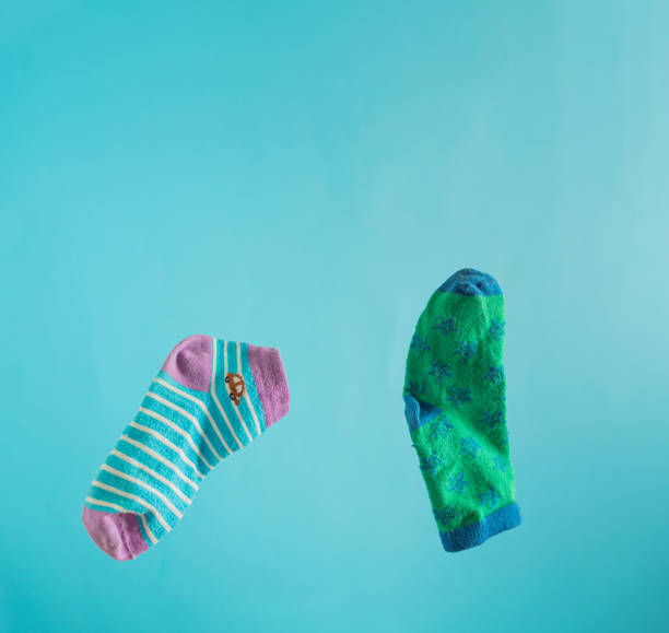 Two children's unpaired socks on a light blue background with copy space. March 21, International Day of People with Down Syndrome. Creative support minimal concept.