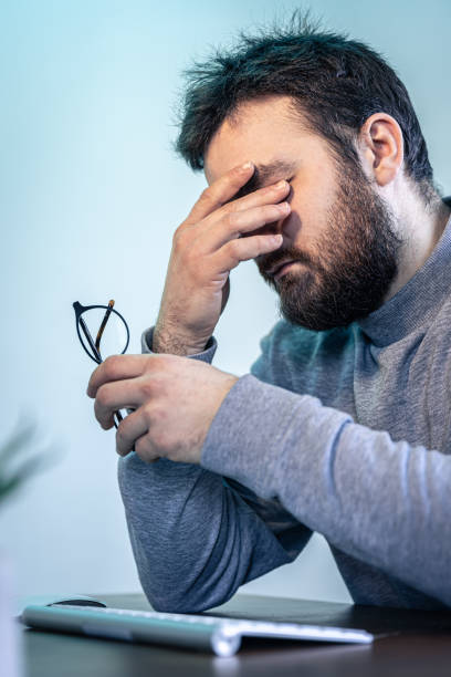 istock A tired man rubs his eyes in front of a computer screen. 1370578359