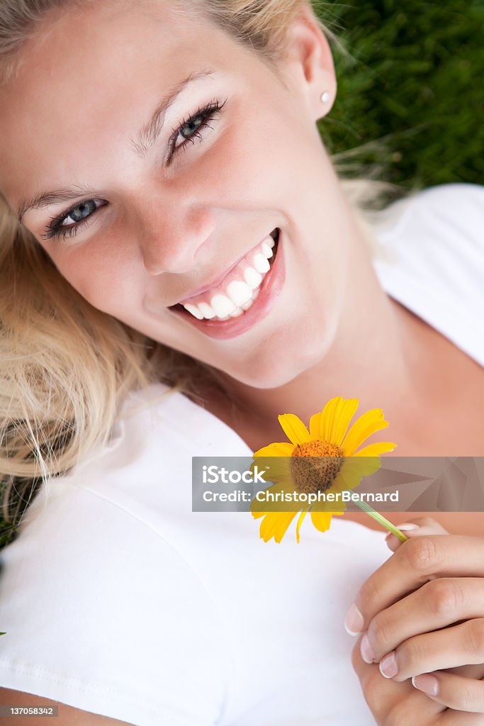 Souriante jeune femme tenant yellow daisy - Photo de 20-24 ans libre de droits