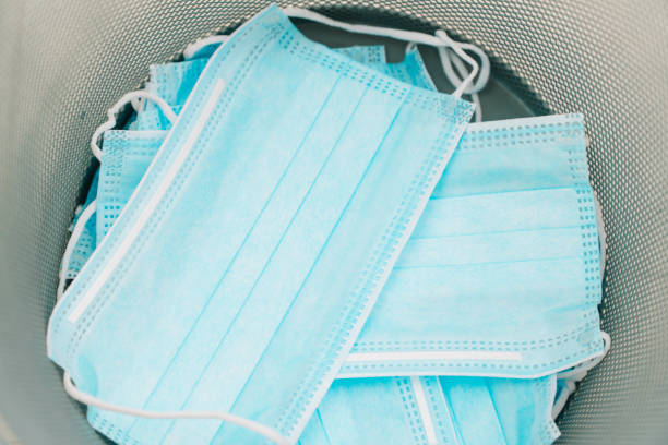 istock Utilization of protection during coronavirus. Blue protective medical mask throwing into the bin. End of quarantine. Waste of epidemic 1370585227