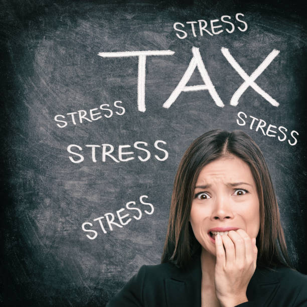 Tax season stress stressed Asian woman biting nails anxious late to file tax paperwork for IRS. Black chalkboard background with text written for income tax returns. stock photo