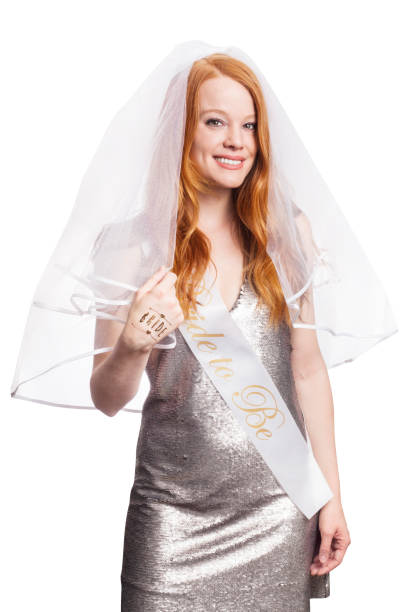 Redhead beautiful woman wearing bride to be bachelorette party outfit with veil and sash on white background stock photo