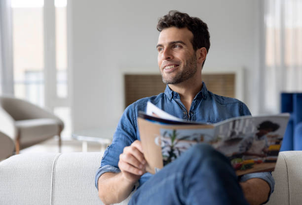 mężczyzna w domu czytający czasopismo w salonie - reading newspaper 30s adult zdjęcia i obrazy z banku zdjęć