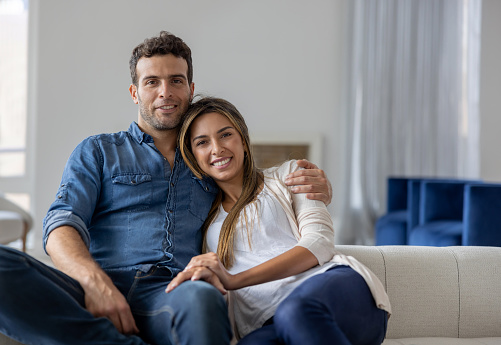 Portrait of a loving Latin American couple relaxing at home and looking at the camera smiling