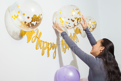 Mother putting up birthday decorations and confetti balloons