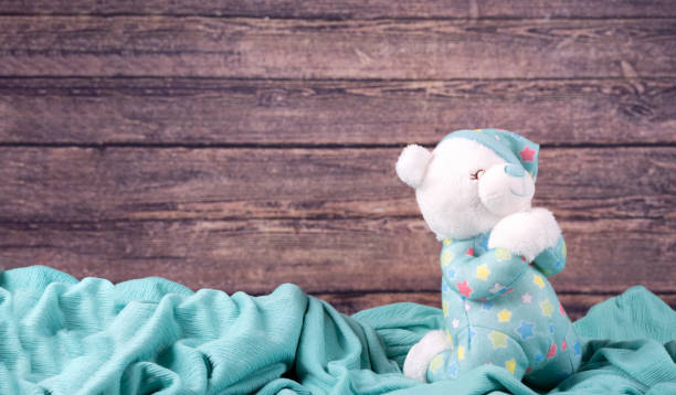 istock Cute white teddy bear pray on blue fabric background. New Born, communion ,confirmation or baptism Greeting Card. 1370594405