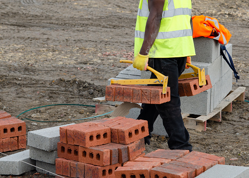 Bricklayers bringing bricks close to his place of work using brick lifters