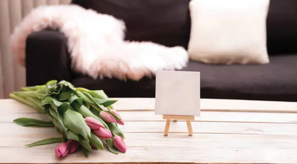 Home decor items in the living room with tulips on the table wooden background.