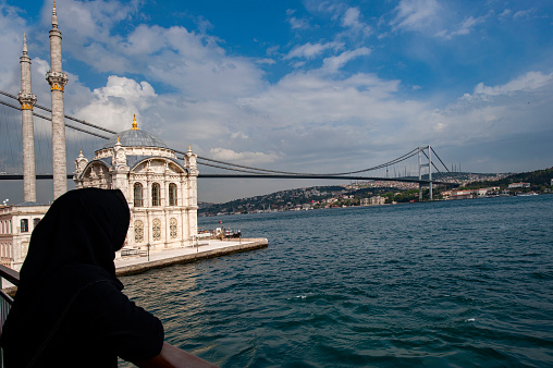 Woman in black chador watching the Bosphorus from the Ortaköy mosque