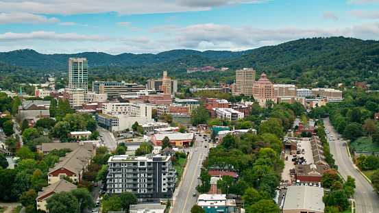 Aerial shot of downtown streets in Asheville, North Carolina with the Blue Ridge mountains in the background.
