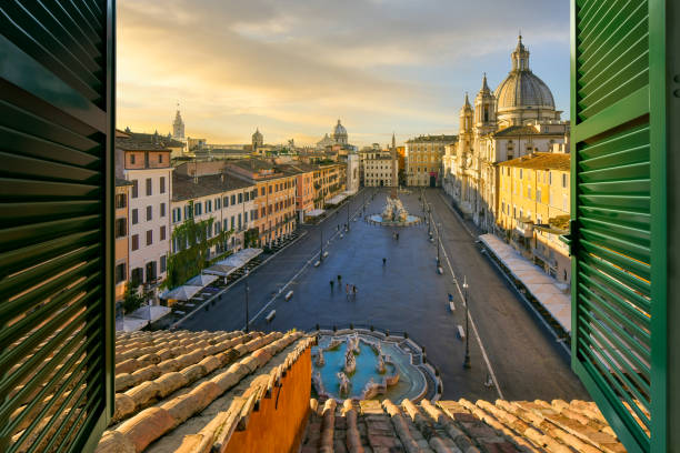 view through an open window with shutters over the piazza navona with historic fountains, churches, cafes and buildings at sunset, in rome, italy. - piazza navona imagens e fotografias de stock