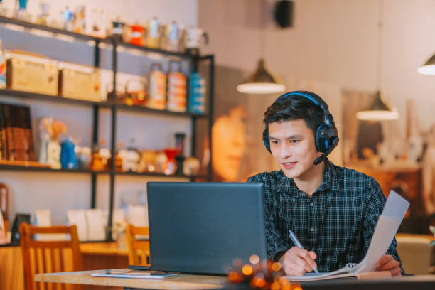 Asian Chinese man video call working with his laptop at cafe