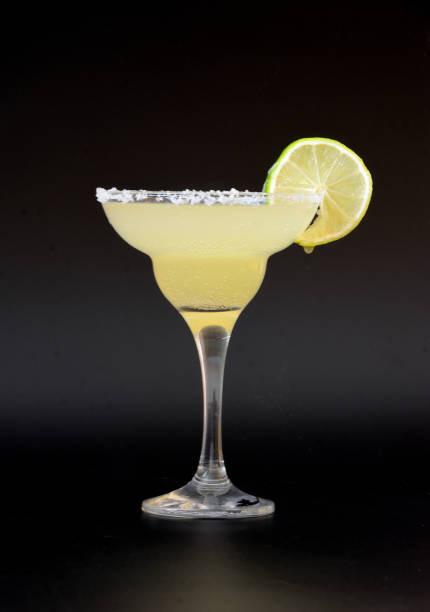 cóctel "margarita" bebida baja en alcohol con sal y una rodaja de lima sobre fondo negro. - cocktail alcohol drink black fotografías e imágenes de stock