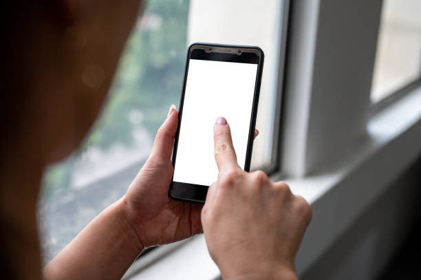 istock Woman hand touching smartphone with blank white screen in home interior, 1370611981