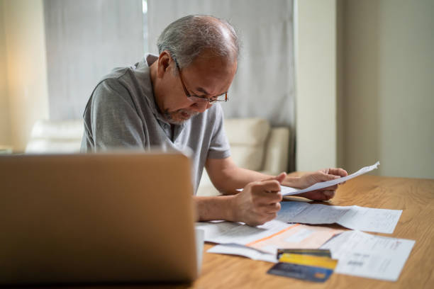 istock Depressed Asian senior elder man feel worried about financial problem. Stressed desperate older grandpa looking frustrated to paperwork and bills think of money debt, budget loss, bankruptcy at home. 1370613949