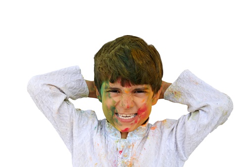 Horizontal photograph of Cutout of a shouting kid in white coloured Kurta smiling with mouth wide open and teeth visible, his hands behing his head, isolated over white. Ideal for posters, greeting cards, postcards related to the Indian Hindu festival of colors - Holi. He has his arms stretched and folded.