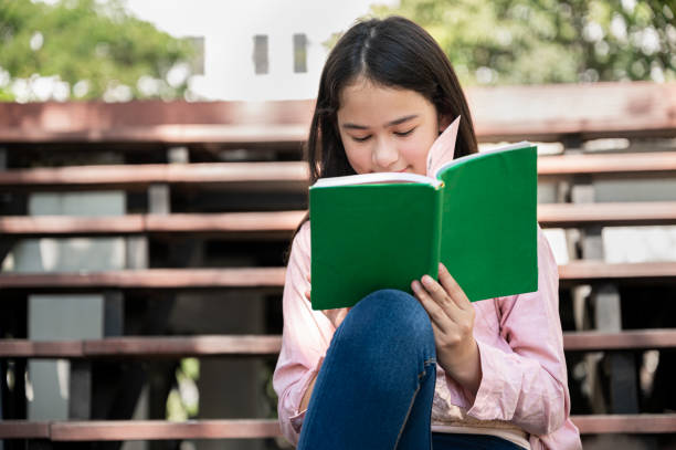 istock Student girl reading book at school park 1370627382