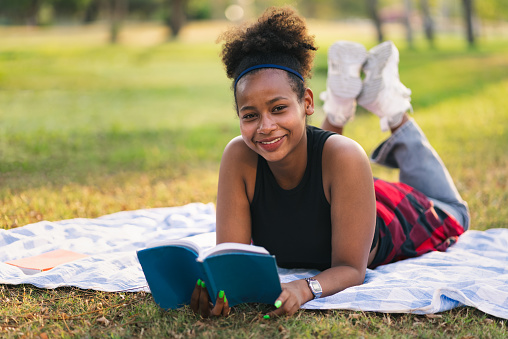 Student girl lie down and reading book in the park