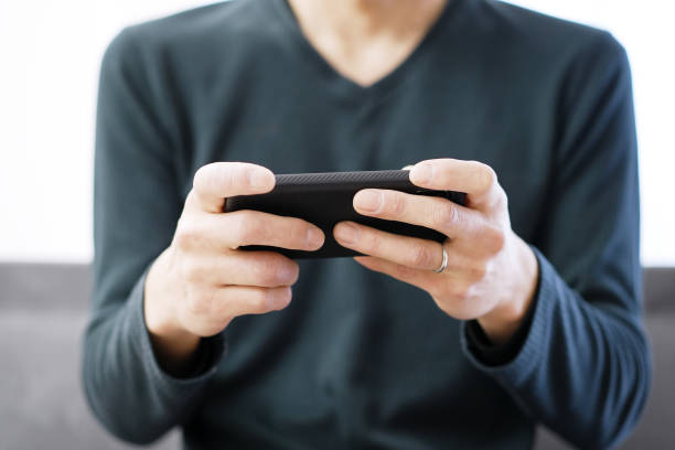 Asian man playing games on his smartphone Asian man playing games on his smartphone handheld video game stock pictures, royalty-free photos & images