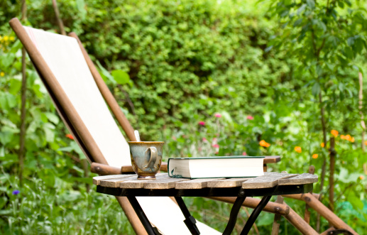 Table with book and cup in the garden.Shallow DOF.