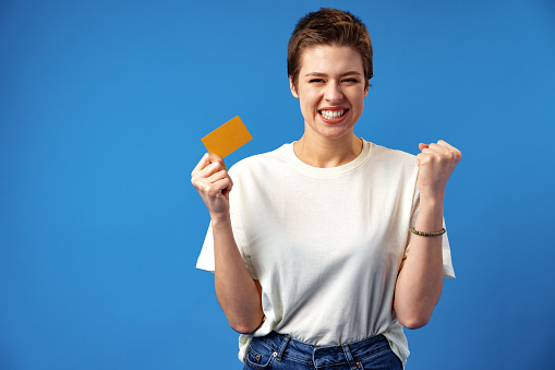 Image of young woman holding business card with copy space on blue background, close up