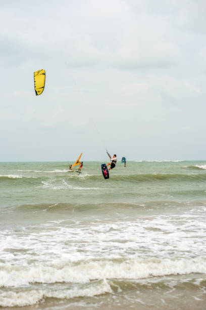 People kite surfing off beach at Sao Miguel Do Gostoso. Three people are pictured in action.