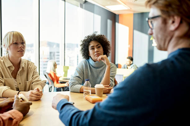 istock Business colleagues conversing at table in open plan office 1370642427