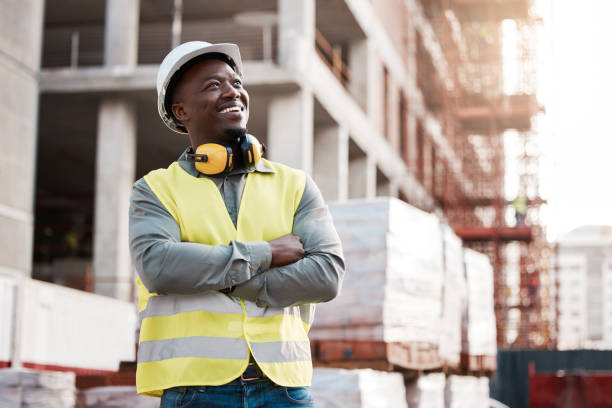 shot of a young male construction worker day dreaming while on site - male african descent africa ethnic imagens e fotografias de stock