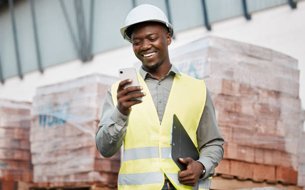 Shot of a young businessman using his smartphone while on a construction site