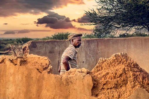 African man standing in front of a ruined house in the village