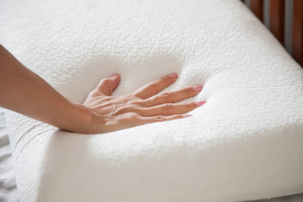 istock woman holding white thin memory foam pillow on white bedsheets 1370645301