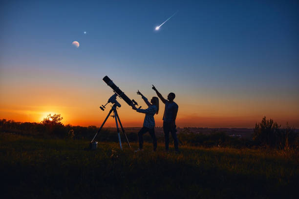 pareja observando estrellas junto con un telescopio astronómico. - lluvia de meteoritos fotografías e imágenes de stock