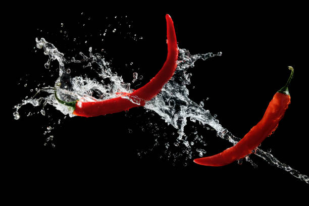 istock Red hot peppers in water splash over black background 1370648649