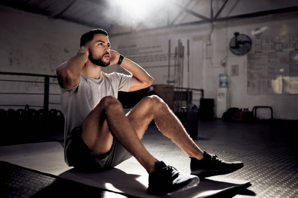 istock Shot of a young man doing crunches in a gym 1370649785