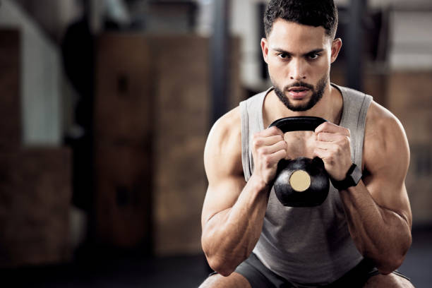 Shot of a young man doing squats with weights in gym