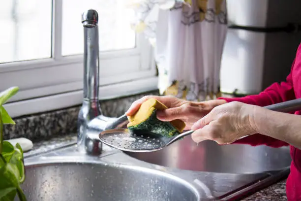 woman washing skimmer in kitchen sink