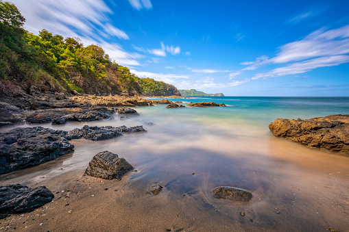 Long exposure, pacific ocean waves on rock in Playa Ocotal, El Coco Costa Rica. Famous snorkel beach. Picturesque paradise tropical landscape. Pura Vida concept, travel to exotic tropical country.