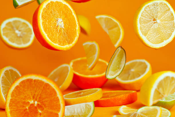 istock Oranges, lemons and limes cut into slices. Citrus vegetables fly on an orange background. Preparing vegetables for juice and cocktails. 1370652572