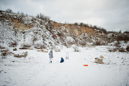 Family plays and sleigh rides in winter outdoor, mother and children having fun.