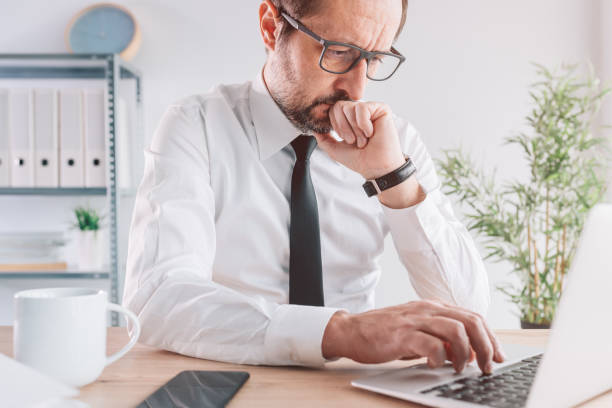 istock Business person working on laptop computer in bright office interior, serious entrepreneur thinking 1370658052