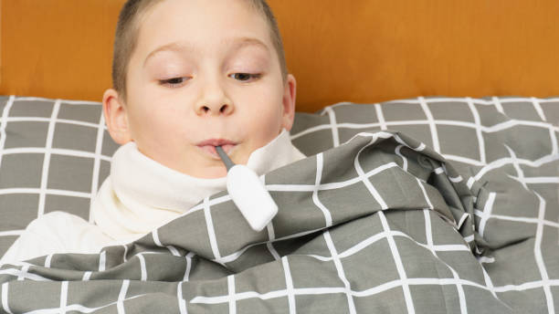 istock sick boy with a thermometer in his mouth. 1370658362