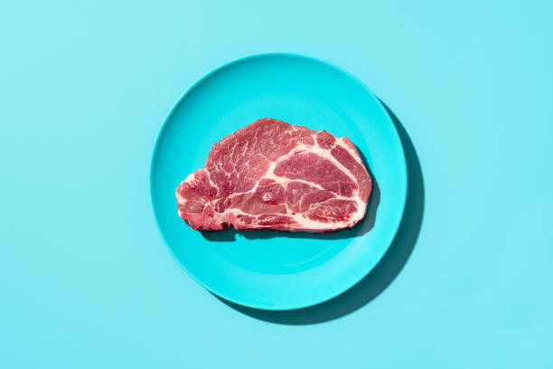 bife de porco cru em um prato, vista superior. bife isolado no fundo azul - fillet meat portion fillet steak - fotografias e filmes do acervo