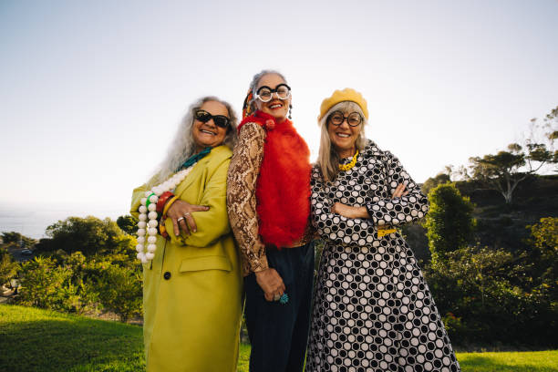 Mature eccentric women smiling happily while standing in a park Mature eccentric women smiling at the camera while standing together in a park. Group of confident elderly women wearing colourful casual clothing. Three stylish senior women enjoying their golden years. eccentric photos stock pictures, royalty-free photos & images